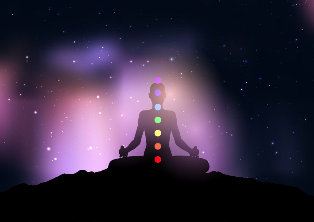 Silhouette of a female with chakra in yoga pose against starry night sky