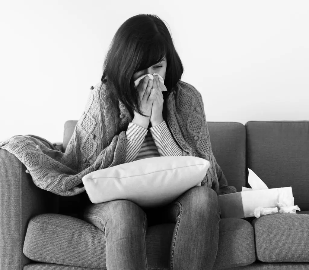 Sick woman sneezing on the sofa 