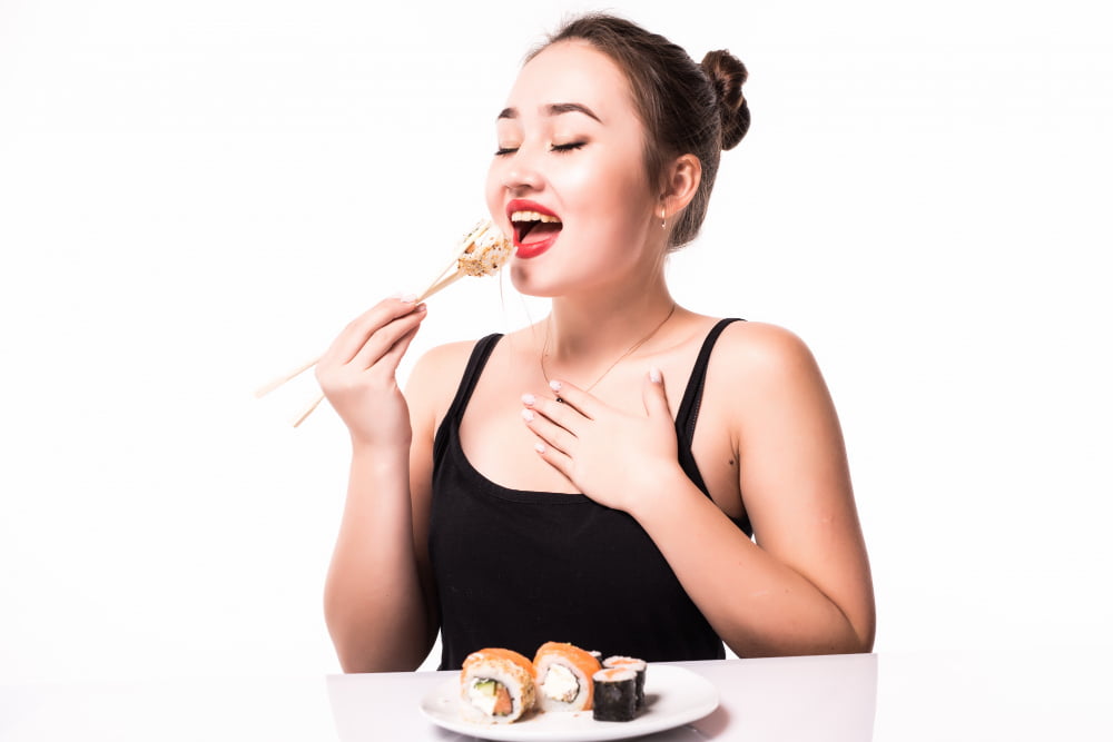 woman eating masago sushi rolls